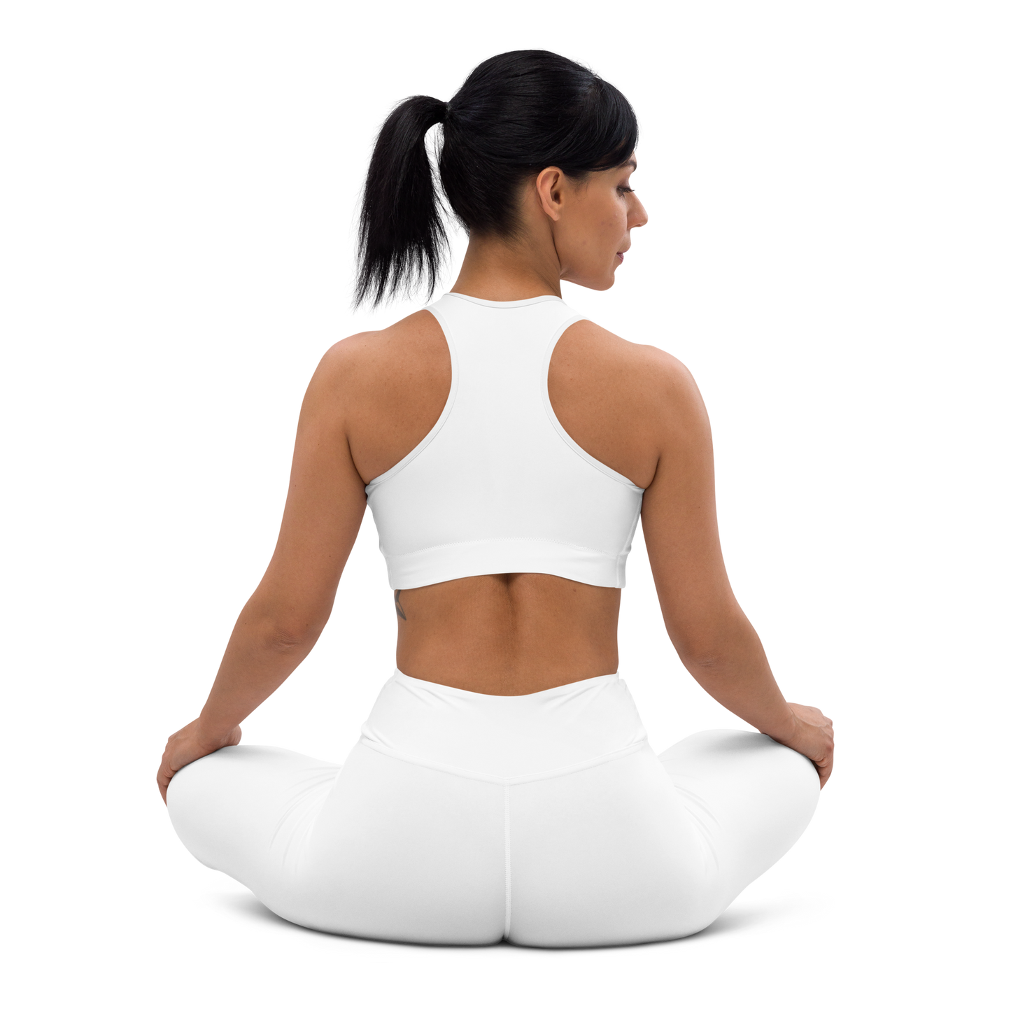 Back view of a woman seated in a lotus pose wearing a white racerback sports bra and matching white high-waist leggings, shown on a white background — activewear apparel.