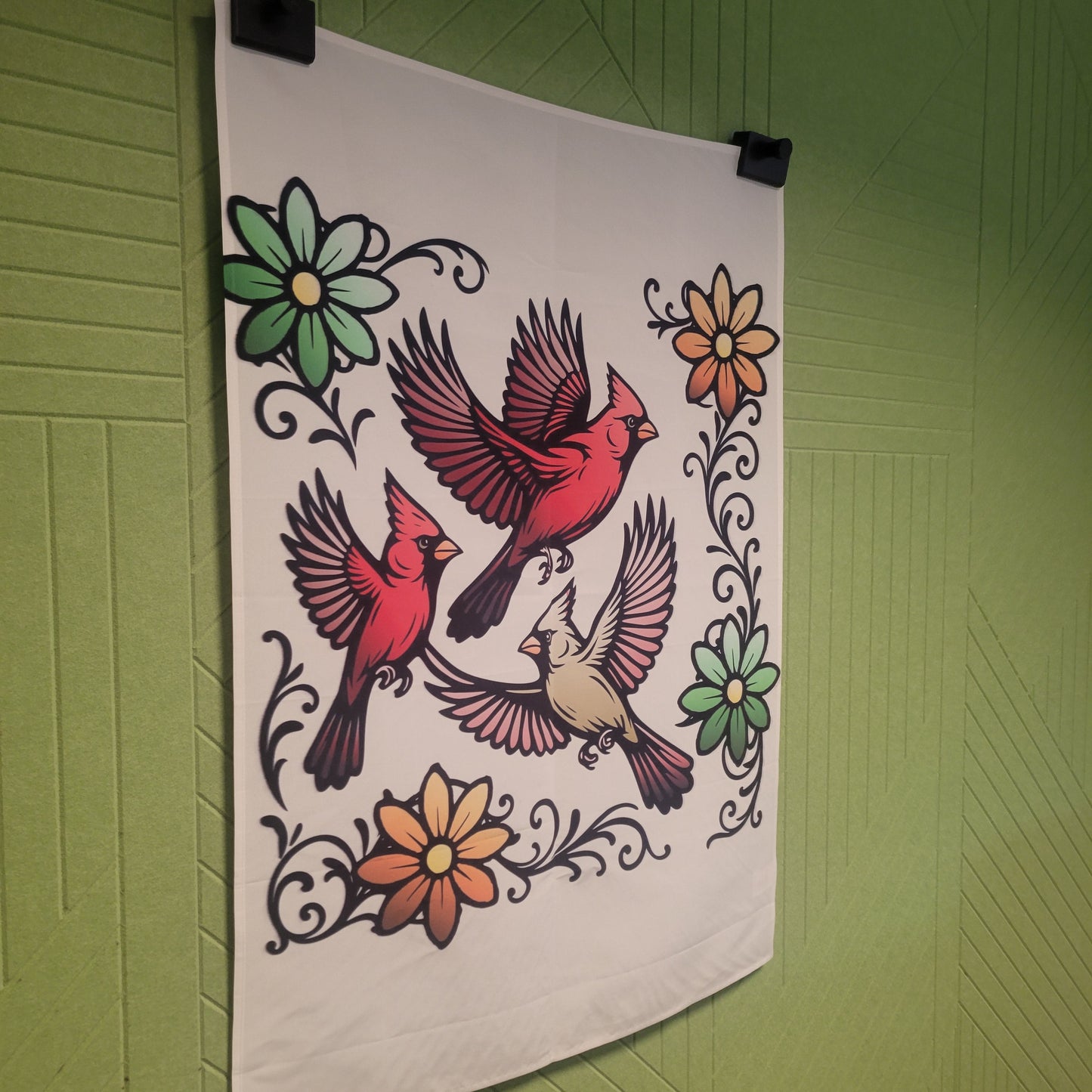 Three flying cardinals shown from a left angle in bold tattoo-style illustration on beige, surrounded by decorative black scrollwork and colorful flowers in green and orange. Wall tapestry.