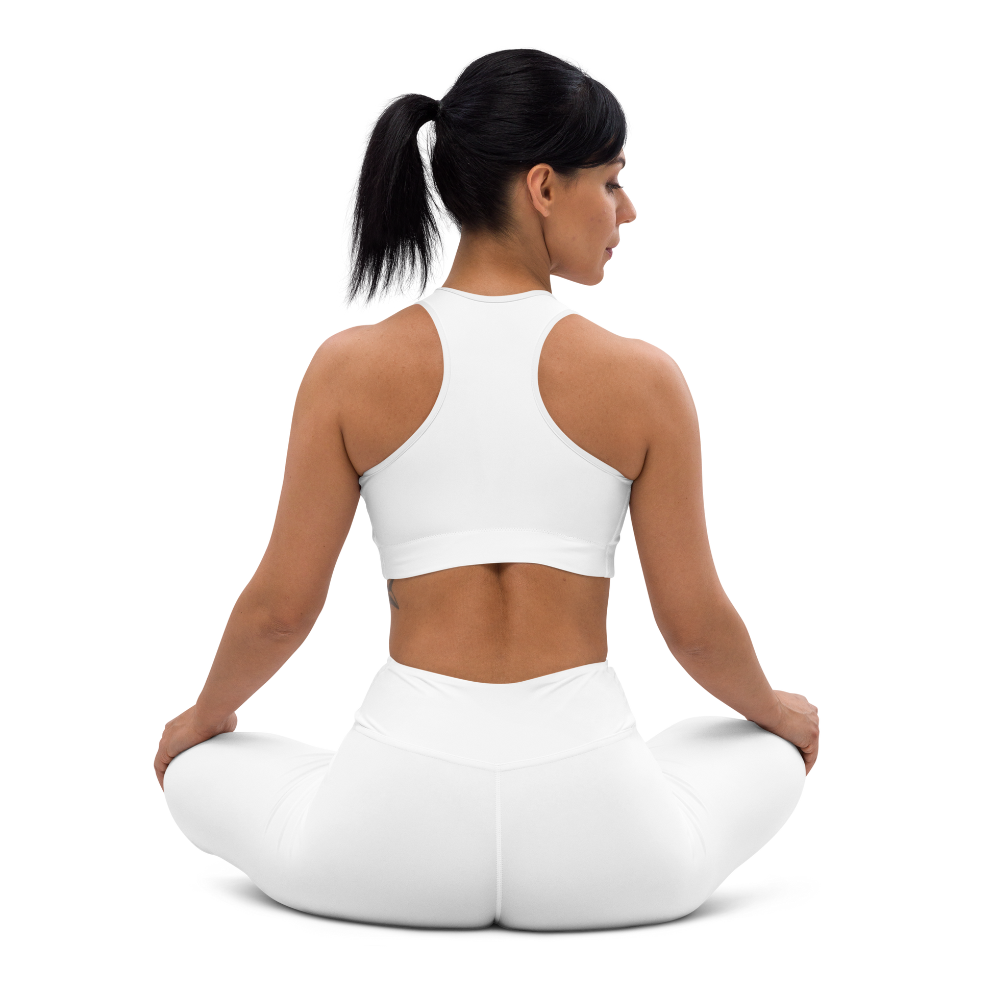 Back view of a woman seated in a lotus pose wearing a white racerback sports bra and matching white high-waist leggings, shown on a white background — activewear apparel.