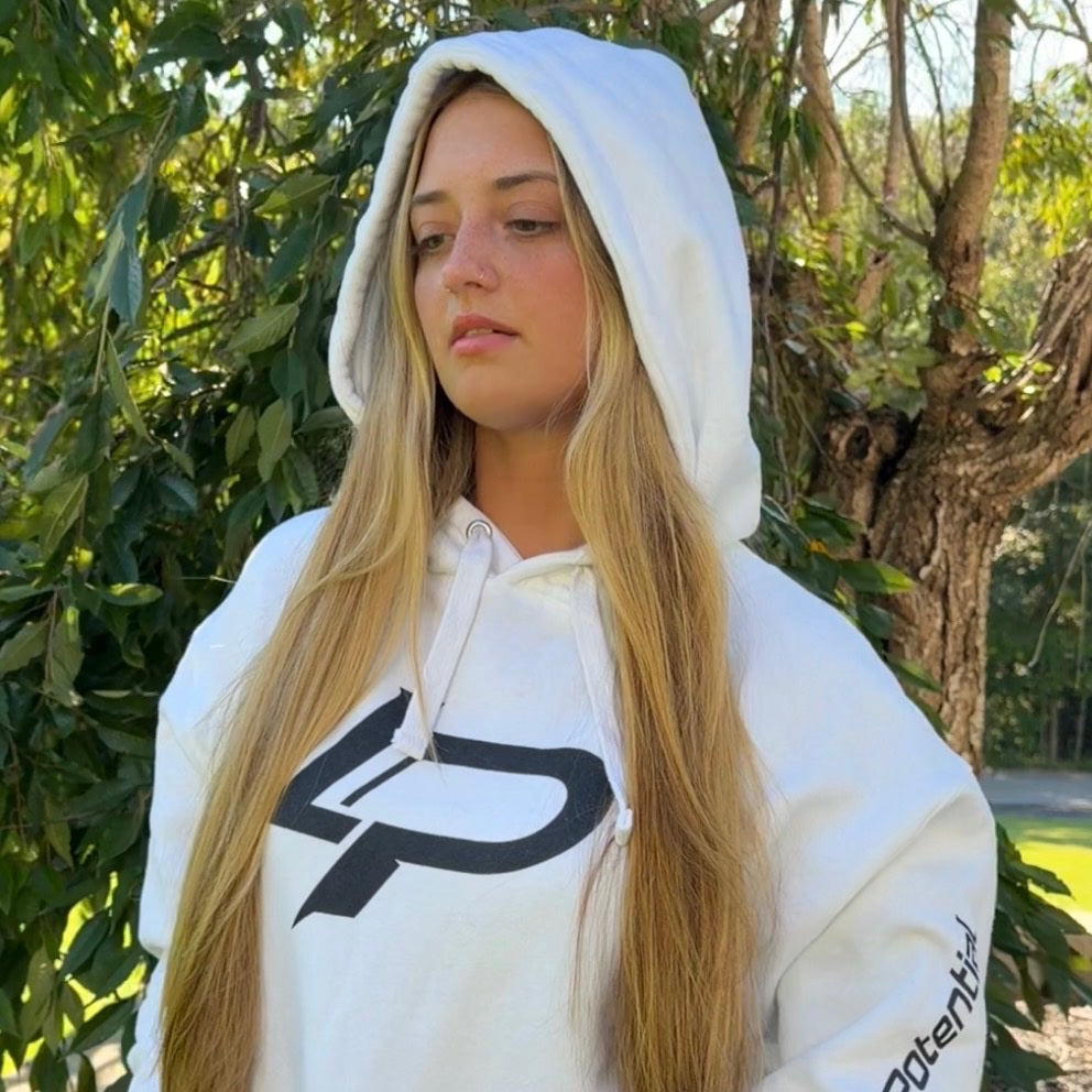 Female model wearing a white pullover hoodie with a bold "LP" logo on the front with a black sleeve print showing the word "potential". Apparel lifestyle photo.