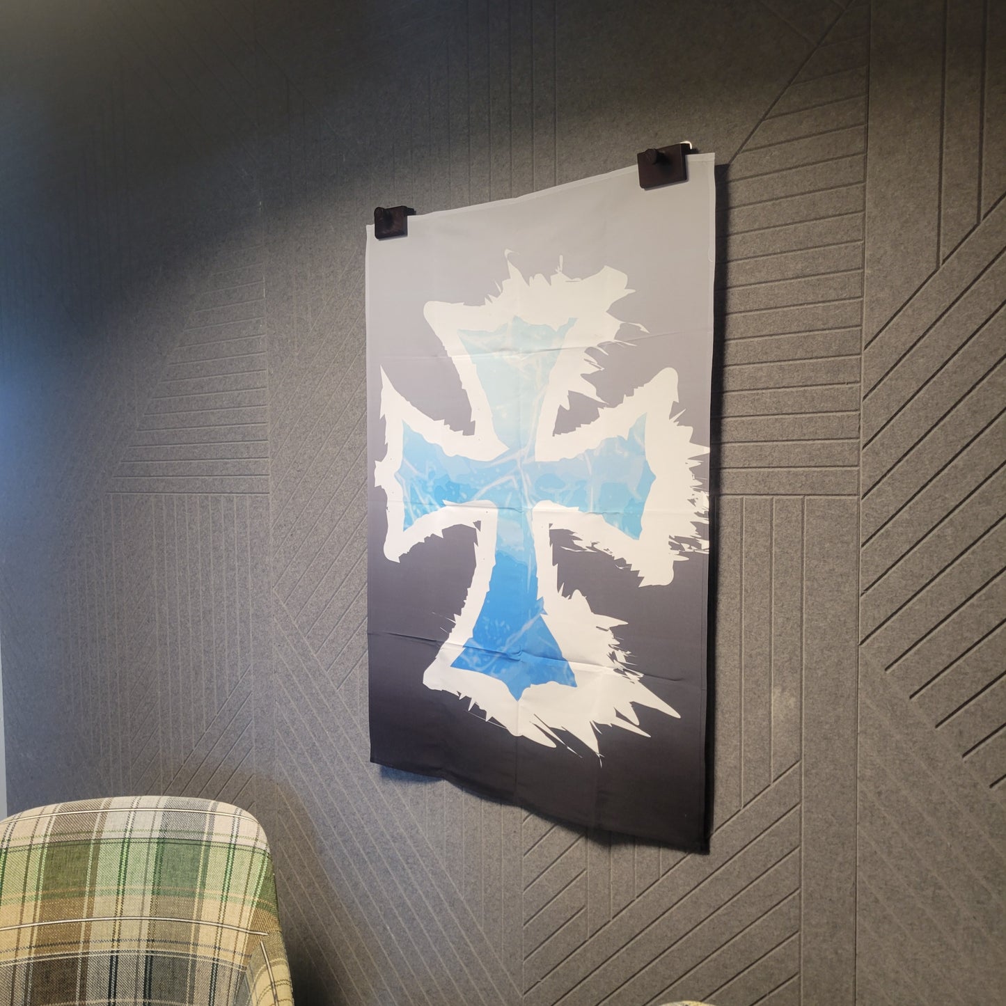 Jagged white cross with icy blue gradient center on a dark gray to black background, displayed hung on a wall as a tapestry.