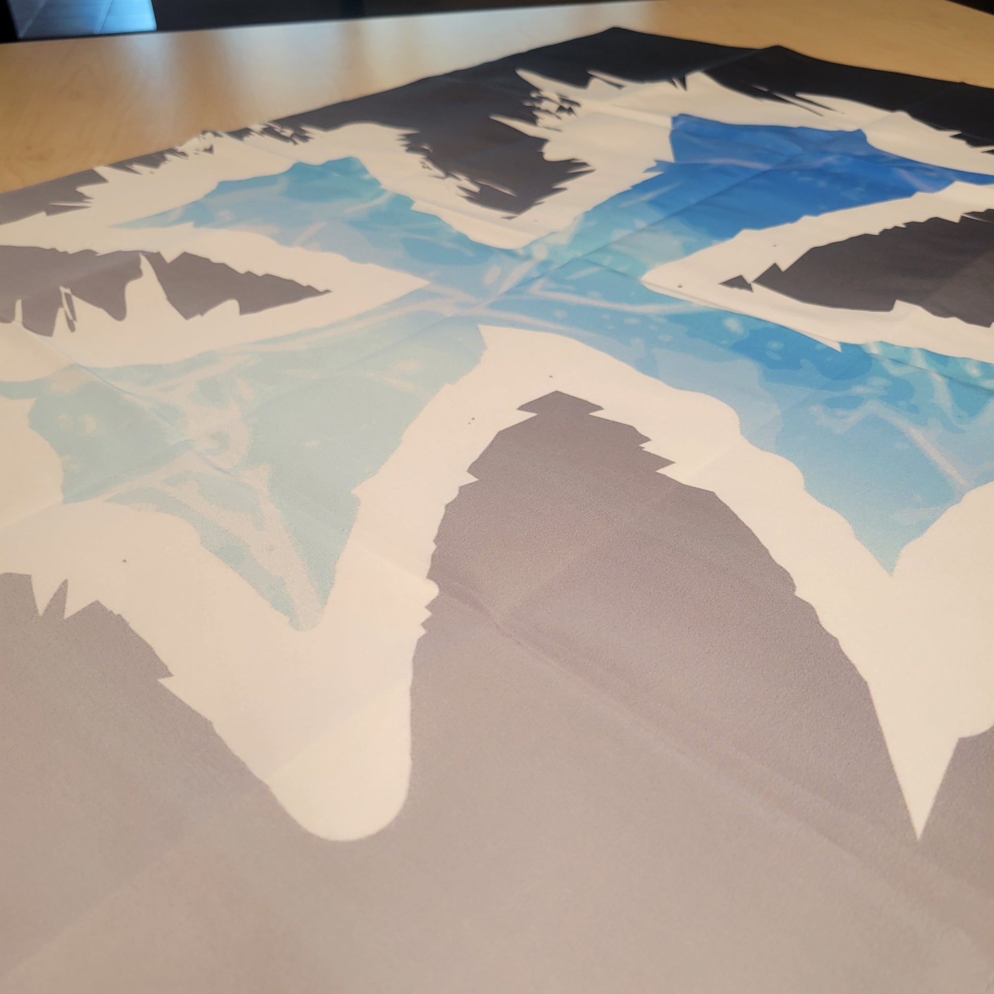Bold geometric design in black, white, and vivid blue tones with jagged edges and icy textures, photographed close up and flat on a table — tapestry.
