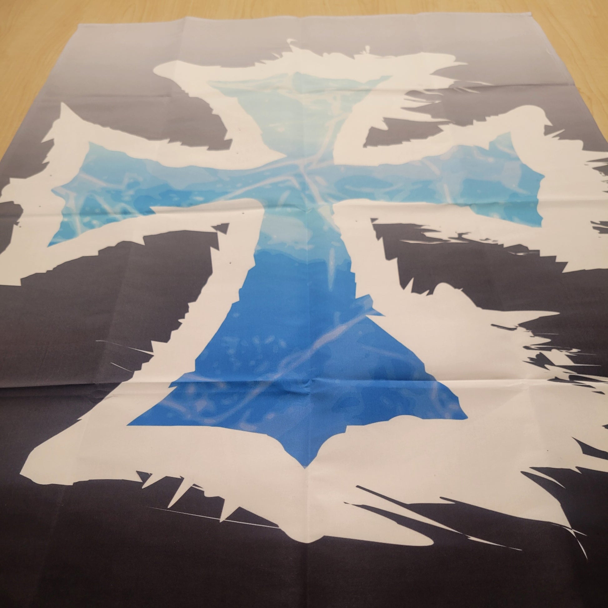Dark fantasy tapestry featuring a bold blue and white geometric cross design with jagged, fractured edges against a black and gray gradient background. Wall tapestry.