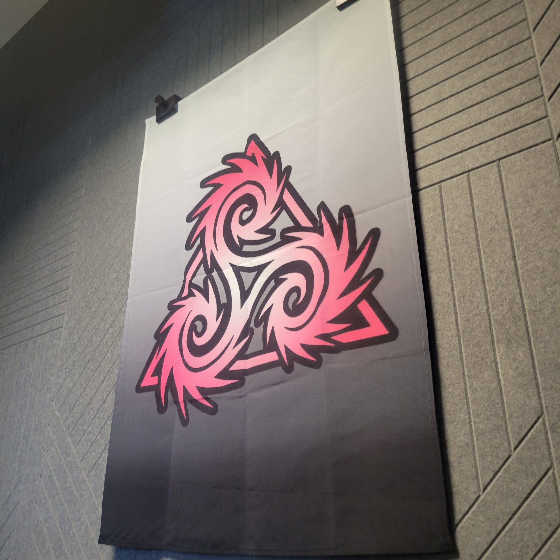Hanging Triskelion-style Norse symbol with swirling pink and black edges on a white-to-charcoal gradient background, wall tapestry.