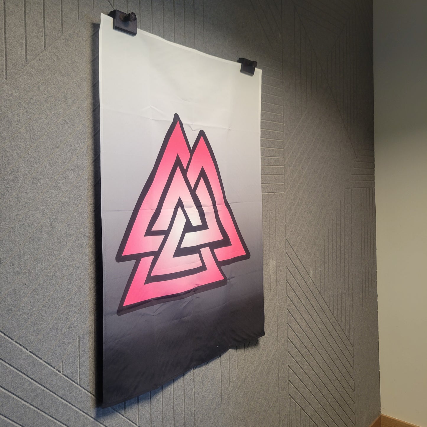Hanging bold pink and black Valknut symbol—three interlocked triangles—centered on a white-to-black gradient background, wall tapestry.
