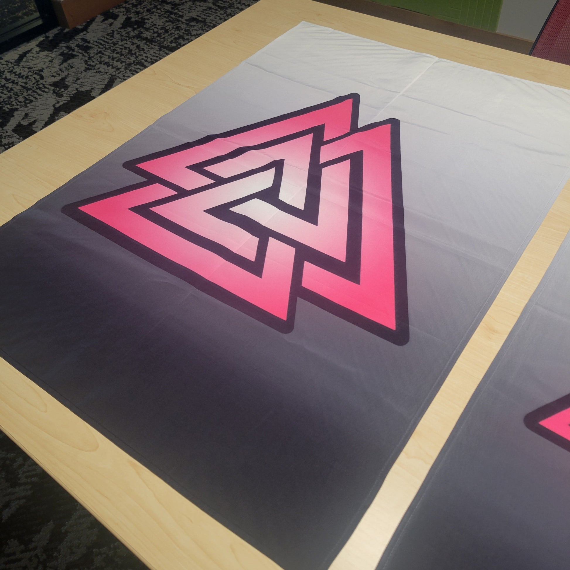 Bold pink-to-white gradient Valknut symbol with dark outline on a gray ombre background, displayed flat on a table — wall tapestry.